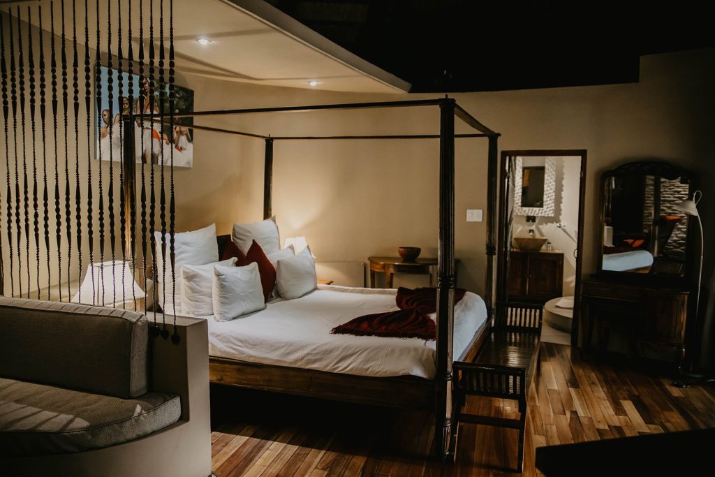 Five-star Mountain Lodge bedroom at Maliba with a four-poster bed and a freestanding bath