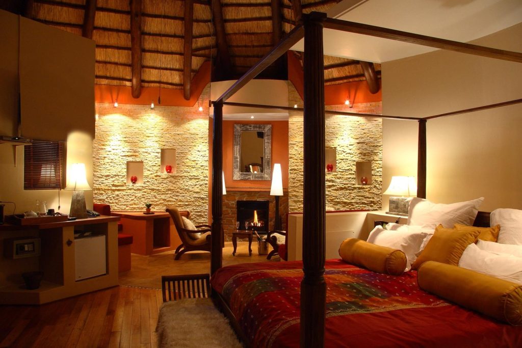 Four-poster bed beside a stone fireplace in a five-star Mountain Lodge room at Maliba