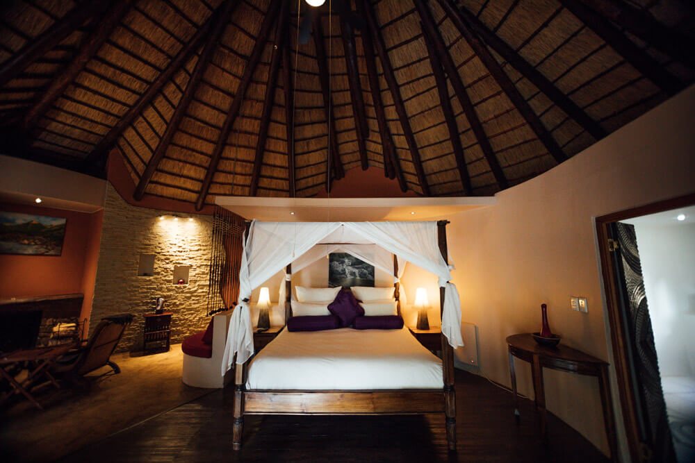Thatched five-star Mountain Lodge room at Maliba with a canopy bed and a sitting area