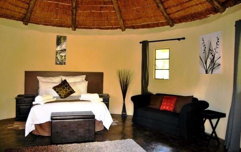 Queen bed and sitting area inside a round Riverside Hut at Maliba