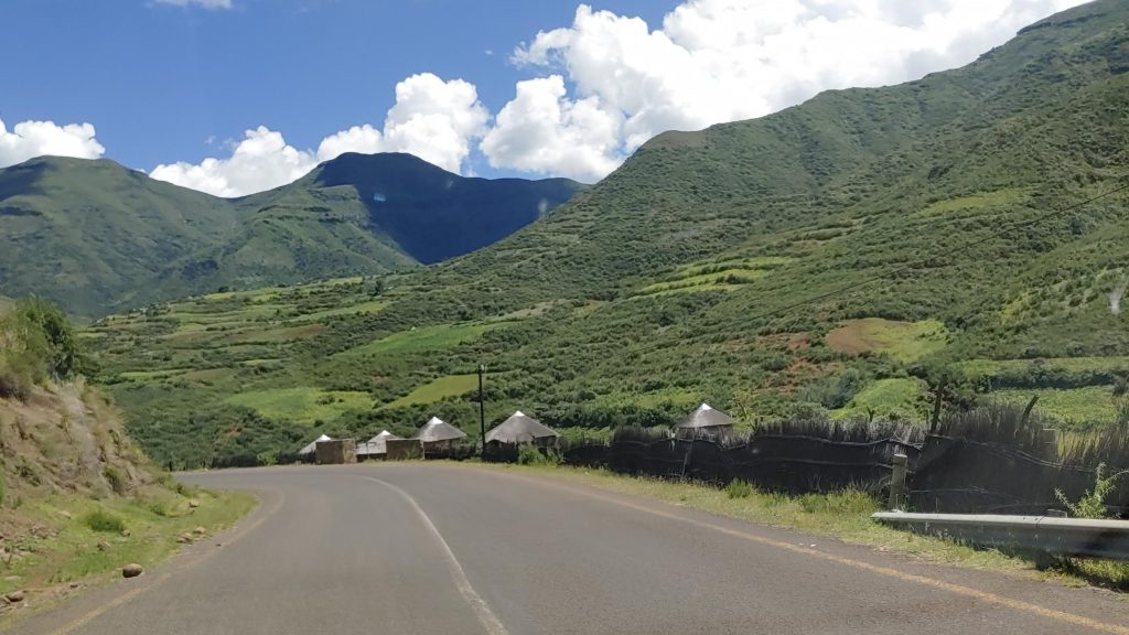 Road through green valleys and thatched rondavels in northern Lesotho